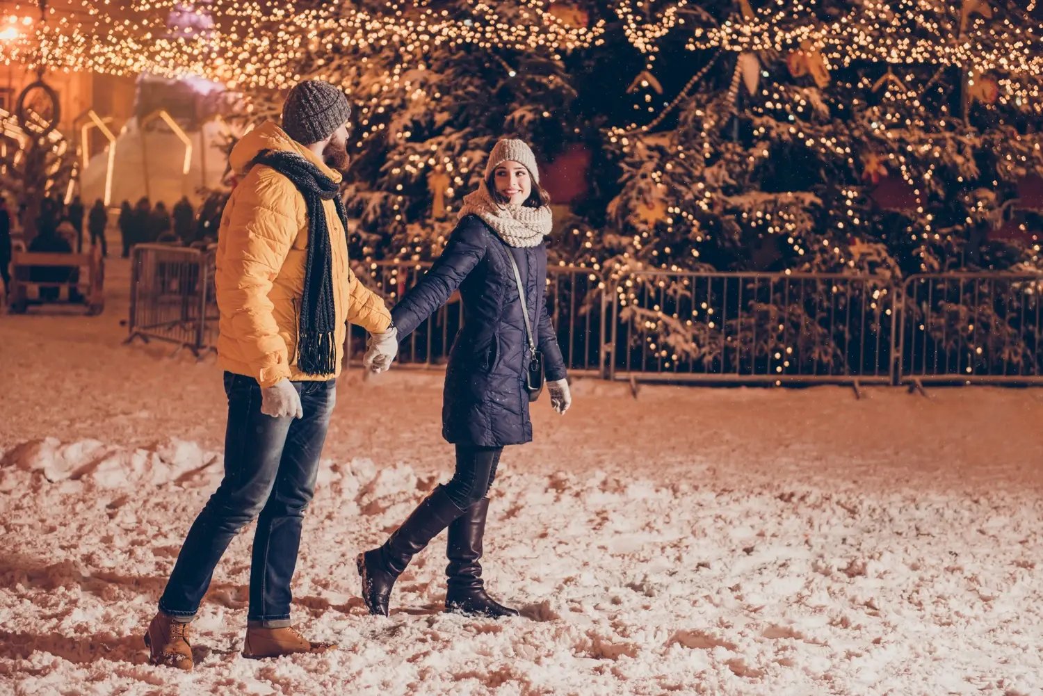 Couple holding hands before Christmas decorations - Image by Roman Samborskyi